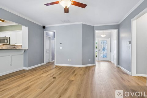 A spacious room with wooden flooring and a ceiling fan.