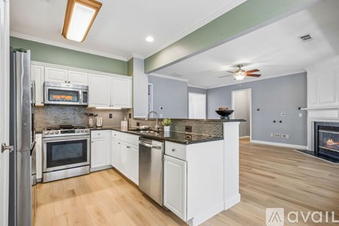 A kitchen with white cabinets and a stainless steel refrigerator.