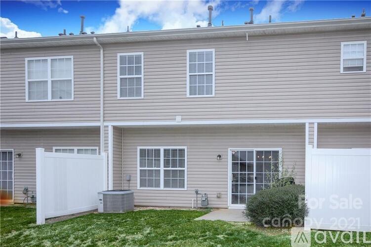 A two-story residential building with a white fence and a sign that says "For Sale".