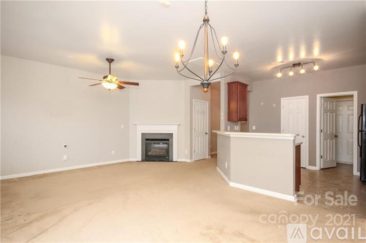 A living room with a fireplace and a chandelier is for sale.