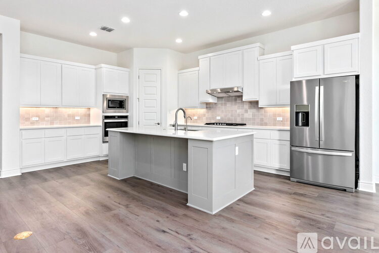A kitchen with white cabinets and a wooden floor.