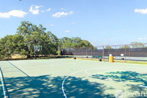 A basketball court with a hoop and a fence in the background.