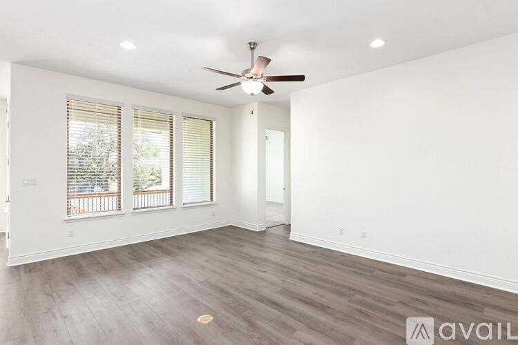 A spacious room with a ceiling fan and wooden flooring.
