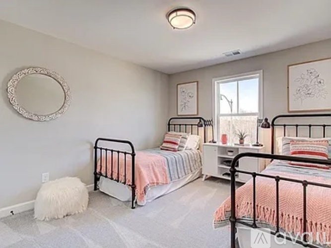 A bedroom with two beds and a round mirror on the wall.