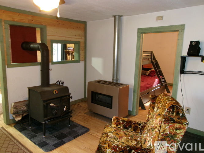A wood stove is in a living room with a couch and a television.