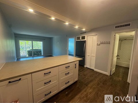 A kitchen with white cabinets and a window.