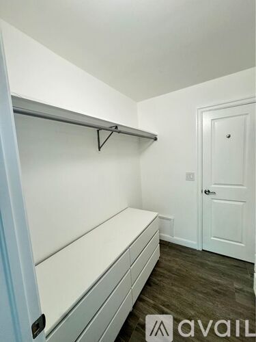 A white closet with a shelf and a door.