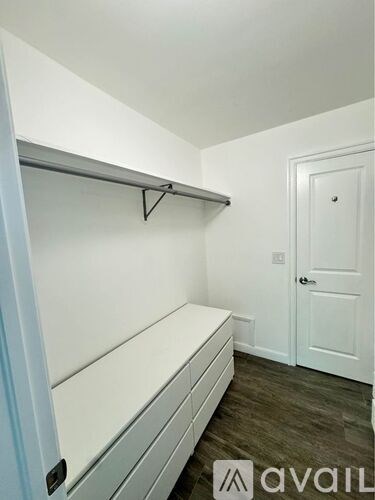 A white closet with a shelf and a door.
