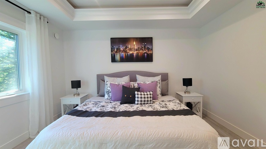 A bedroom with a large bed and a picture of a cityscape on the wall.