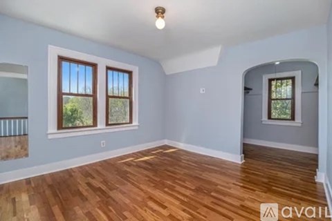 A room with wooden floors and two windows.