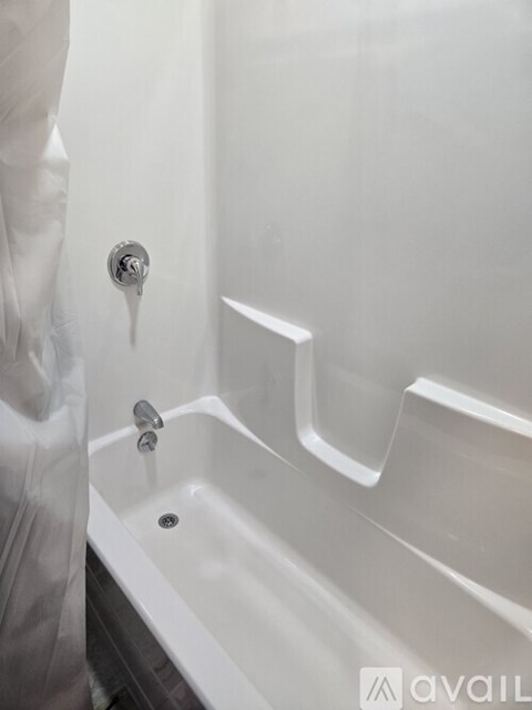 A white bathtub with a shower head and a drain.