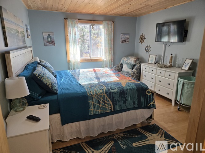 A bedroom with a bed, a chair, and a television.