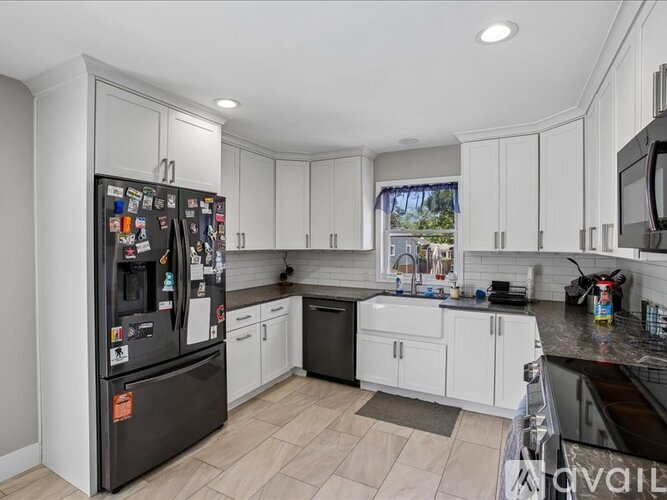 A spacious room with a carpeted floor and two windows.