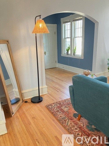 A lamp with a yellow lampshade stands on a wooden floor in a room.