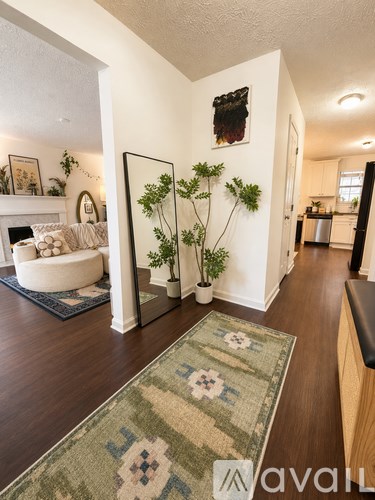 A living room with a rug on the floor and a plant on the side table.