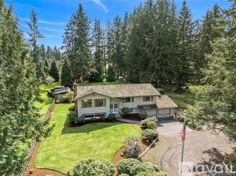 A house with a flag on the lawn is surrounded by trees.