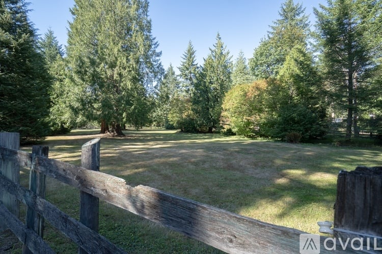 A wooden fence in a grassy field with trees in the background.