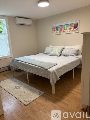 A bedroom with a bed, pillows, and a rug.