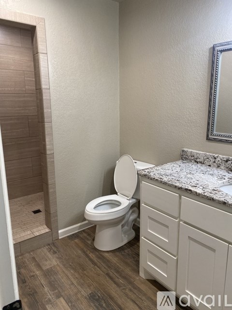 A white toilet in a bathroom with a marble countertop and a mirror above it.