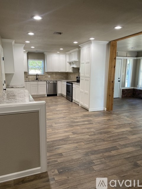 A kitchen with white cabinets and a wooden floor.