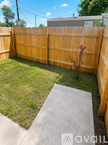 A backyard with a wooden fence and a concrete path.