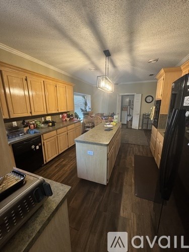 A kitchen with wooden cabinets and a black refrigerator.