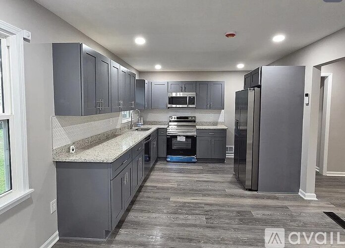 A kitchen with grey cabinets and a granite countertop.