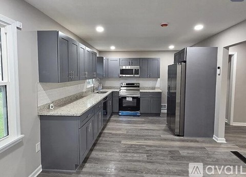 A kitchen with grey cabinets and a granite countertop.
