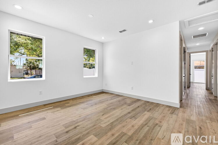 A spacious room with wooden flooring and white walls.