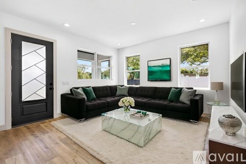 A modern living room with a black couch and a glass coffee table.