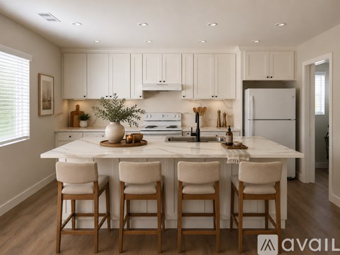 A kitchen with white cabinets and a white island with four chairs.