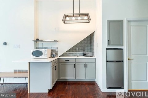 A kitchen with white cabinets and a wooden floor.