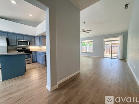 A spacious kitchen with dark blue cabinets and a light wood floor.