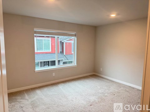 A room with a window showing a red building outside.