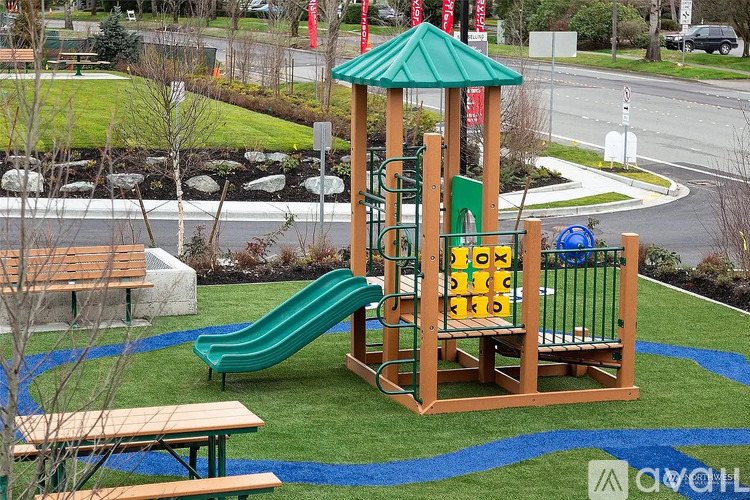 A playground with a green slide and a wooden structure.