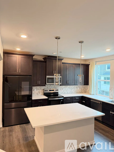 A modern kitchen with dark brown cabinets and stainless steel appliances.
