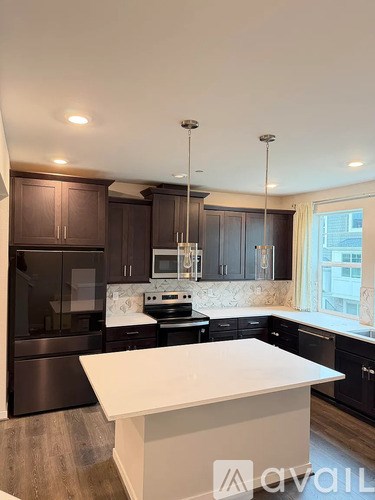 A modern kitchen with dark brown cabinets and stainless steel appliances.