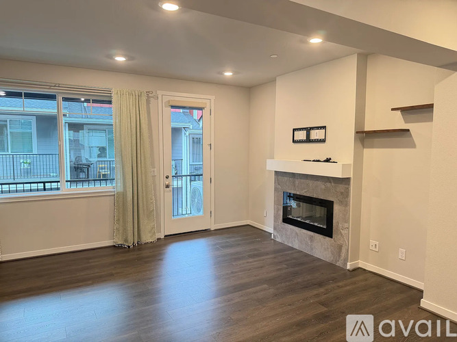 A spacious living room with a fireplace and a view of the outside through the window.