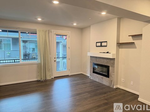 A spacious living room with a fireplace and a view of the outside through the window.
