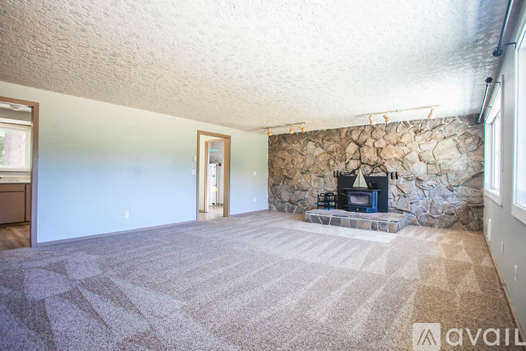 A living room with a stone fireplace and carpeted floor.