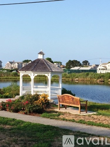 A gazebo with a bench sits in front of a lake.