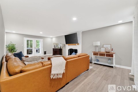 A living room with a brown leather couch and a white fireplace.
