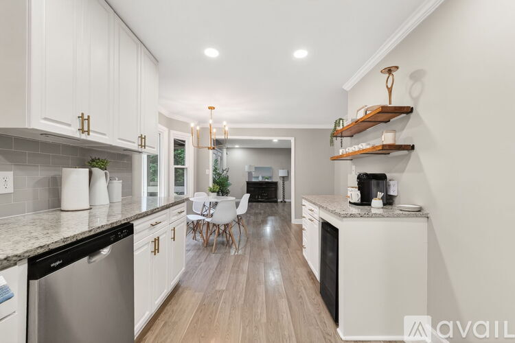 A modern kitchen with white cabinets and a wooden shelf.