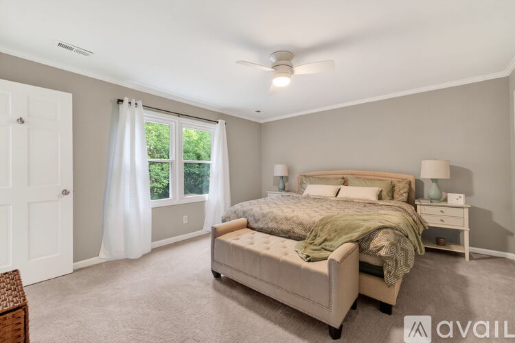 A bedroom with a large bed and a window with curtains.