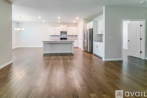 A spacious kitchen with white cabinets and a wooden floor.