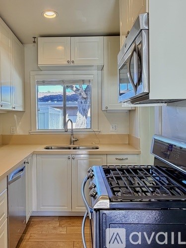 A kitchen with white cabinets and a black Avail stove top.