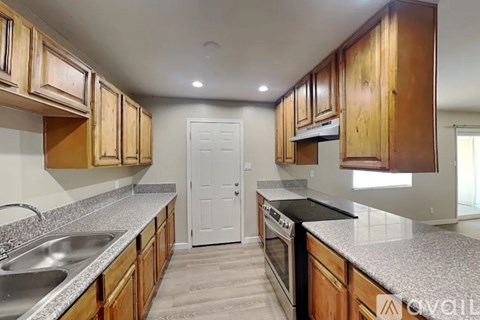 A kitchen with wooden cabinets and a white door in the background.
