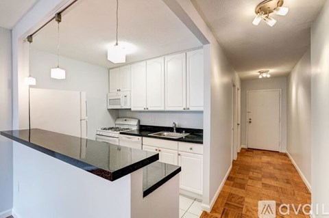 A kitchen with white cabinets and black countertops.