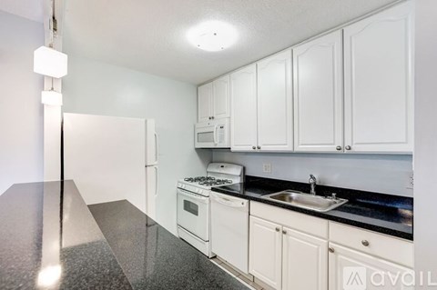 A kitchen with white cabinets and black countertops.