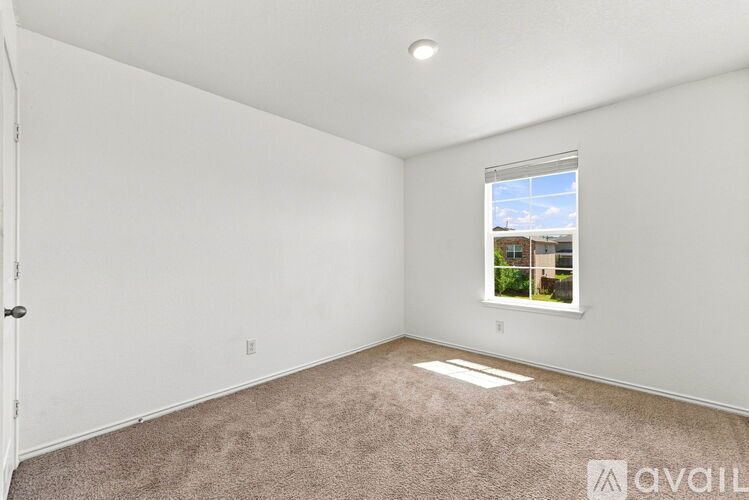 A room with a carpeted floor and a window showing a building outside.
